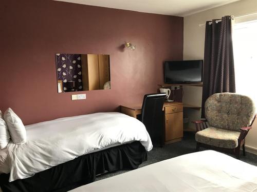 a hotel room with a bed and a chair at The Old Coach House in Buckie