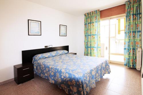 1 dormitorio con 1 cama y una ventana con cortinas en Apartamentos Indasol, en Salou