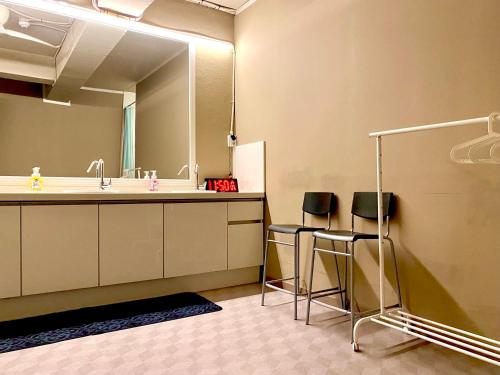 a bathroom with a sink and a mirror and two stools at Sohostel Korea in Busan