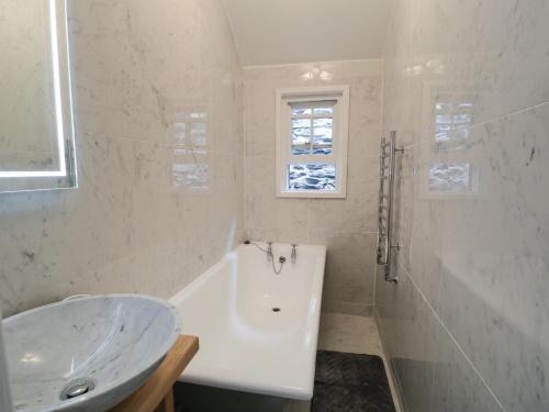 une salle de bain blanche avec une baignoire et un lavabo dans l'établissement Wenallt, à Porthmadog