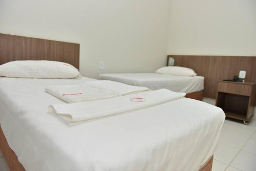 two beds in a hotel room with white towels on them at Hotel Império in Paranaíba