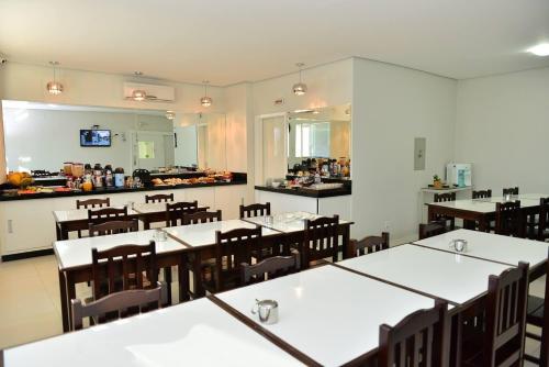 a dining room with tables and chairs and a kitchen at Hotel Império in Paranaíba