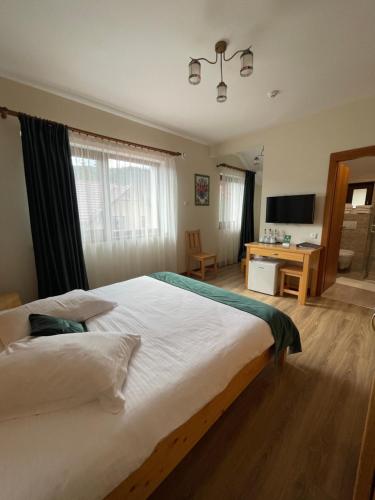 a bedroom with a large white bed and a desk at Villa Montana Borsec - Vedere Munte in Borsec
