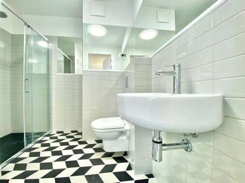 a white bathroom with a sink and a toilet at H11 Aparthotel in Kraków