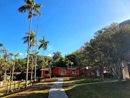 a road in front of a red house with palm trees at Saison Resort & Spa in Itaipava