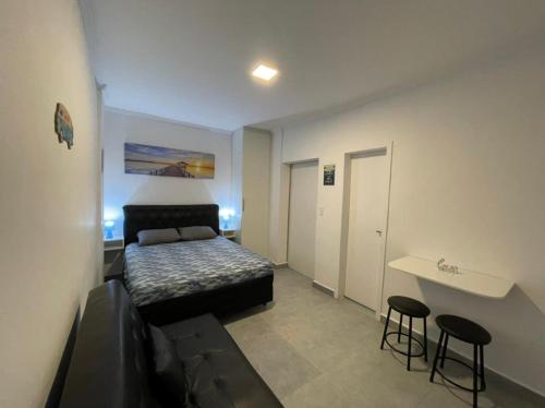 um quarto com uma cama, uma mesa e bancos em Kitnet Premium Canto do Forte - Praia Grande na Praia Grande