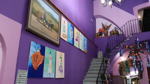 a purple wall with pictures and stairs in a store at Hotel Posada Don Matías in Oaxaca City