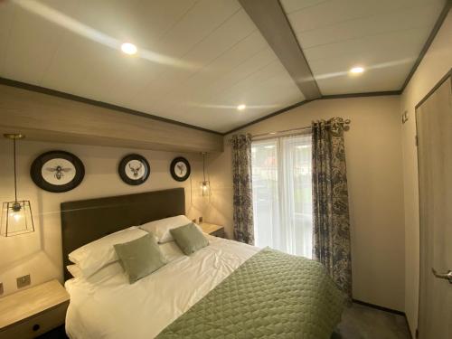1 dormitorio con 1 cama y 2 relojes en la pared en Teviotdale Lodge at Lilliardsedge Holiday Park, en Jedburgh