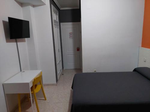 a room with a bed and a desk and a tv at Hotel Cervantes in Mahora