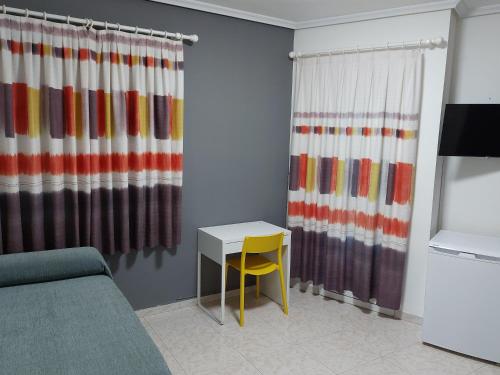 ein Wohnzimmer mit einem Tisch und einem gelben Stuhl in der Unterkunft Hotel Cervantes in Mahora