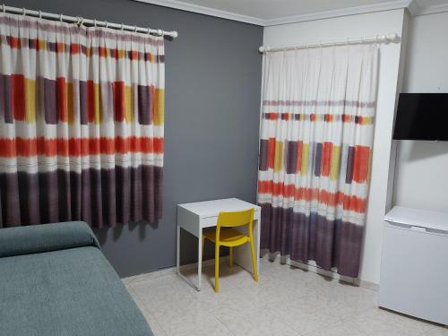 a living room with a table and a yellow chair at Hotel Cervantes in Mahora