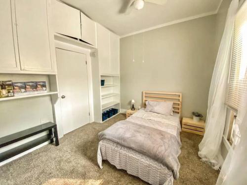 Schlafzimmer mit einem Bett, weißen Schränken und einem Fenster in der Unterkunft Charming Bungalow 