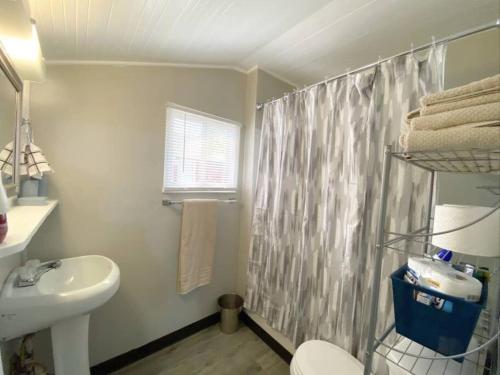 a bathroom with a sink and a shower curtain at Charming Bungalow 