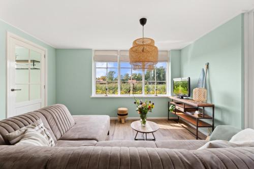 a living room with a couch and a tv at Beach & Forest Retreat -Domburg- in Oostkapelle