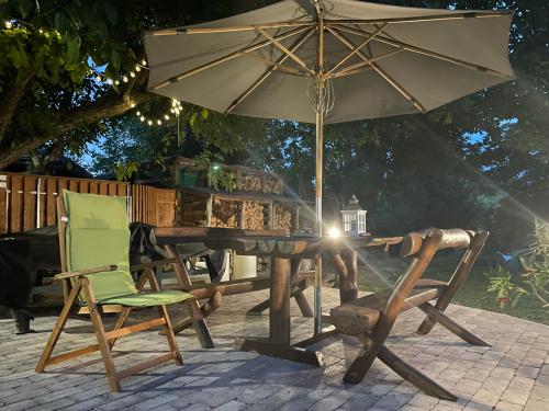 a table with an umbrella and chairs on a patio at Bakonyi Vadász Háza in Bakonykúti