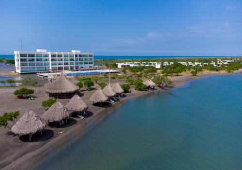 a beach with some straw umbrellas and a building at Marina Puerto Velero in Tubará
