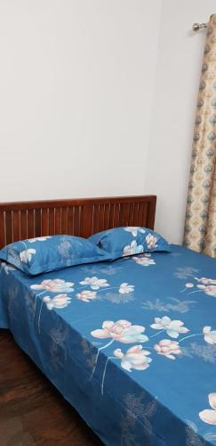 a bed with a blue comforter with flowers on it at Sri Krishna Palace in Mangalore