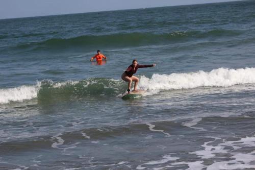 a woman riding a wave on a surfboard in the ocean at Un Dia Boutique Resort in Playas