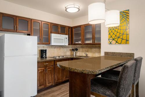 a kitchen with a table and a refrigerator at Staybridge Suites Oklahoma City-Quail Springs by IHG in Oklahoma City