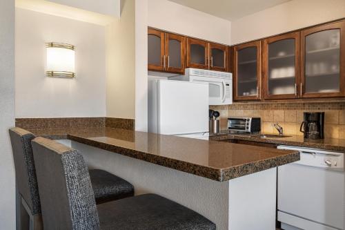 a kitchen with a counter and a white refrigerator at Staybridge Suites Oklahoma City-Quail Springs by IHG in Oklahoma City