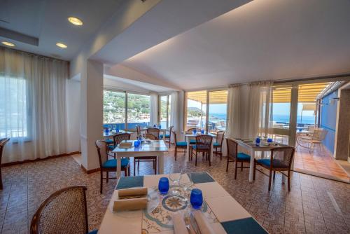 a restaurant with tables and chairs and large windows at Hotel La Stella in Seccheto