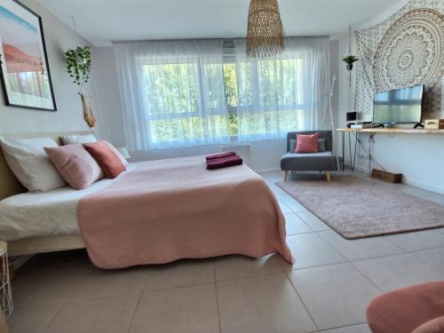 a bedroom with a large bed with a pink blanket at L'AMAZONIE - ROISSY CDG - Parc Astérix - Paris in Moussy-le-Neuf