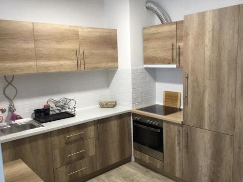 una cocina con armarios de madera y fregadero en Apartman * VICTORY * en Banja Luka