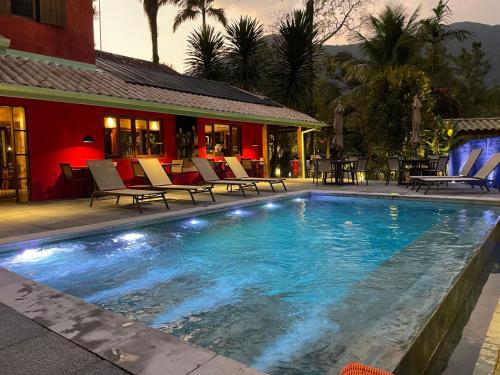 a swimming pool with chairs and a house at Pousada Refúgio de Maresias in Maresias