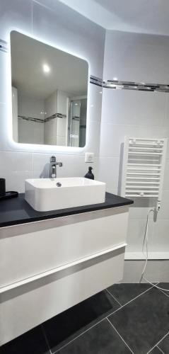une salle de bain blanche avec un lavabo et un miroir dans l'établissement App 11 Mulhouse centre , 4 personnes, à Mulhouse