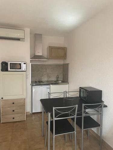 a kitchen with a table and chairs in a room at Appartement T1 in LʼÎle-Rousse