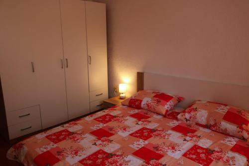 a bedroom with a bed with a red and white quilt at Apartments by the sea Drvenik Veliki, Drvenik - 19229 in Drvenik Veli