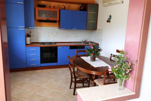 eine Küche mit blauen Schränken und einem Tisch mit Stühlen in der Unterkunft Apartments by the sea Drvenik Veliki, Drvenik - 19229 in Drvenik Veli