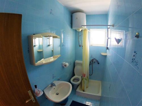 Baño azul con lavabo y aseo en Apartments and rooms with parking space Lopar, Rab - 19238 en Lopar