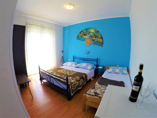 Habitación azul con 2 camas y una botella de vino en Apartments and rooms with parking space Lopar, Rab - 19238 en Lopar