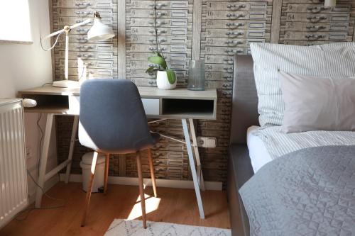 a desk with a blue chair next to a bed at Teubel apartman 5 in Székesfehérvár