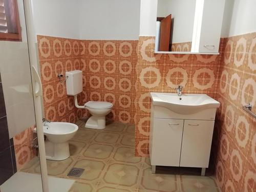 een badkamer met een wastafel, een toilet en een spiegel bij Apartments by the sea Nin, Zadar - 19103 in Nin