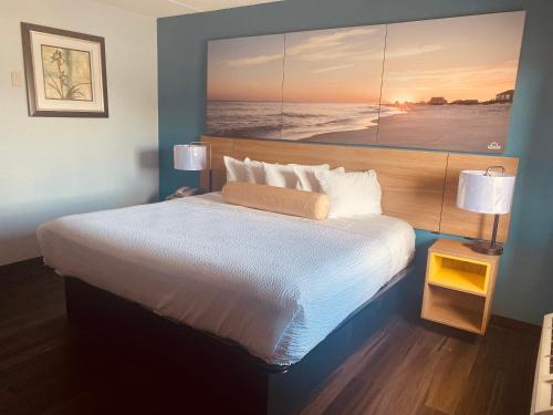 a bedroom with a large bed with a painting on the wall at Days Inn by Wyndham Queensbury/Lake George in Queensbury