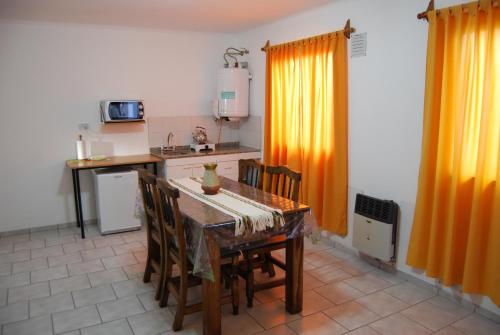a kitchen with a table and chairs and a kitchen with orange curtains at Apartment Al Sur in Malargüe