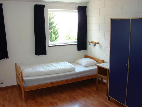 Cette petite chambre comprend un lit et une fenêtre. dans l'établissement B&B Snow View Lodge, à Medendorf