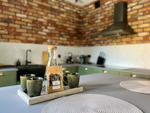 a kitchen with a table with cups and a bottle at Apartament Hansa Klossa in Olsztyn