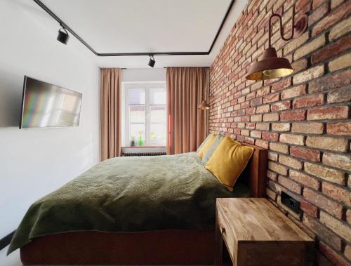 a bedroom with a brick wall and a bed and a table at Apartament Hansa Klossa in Olsztyn