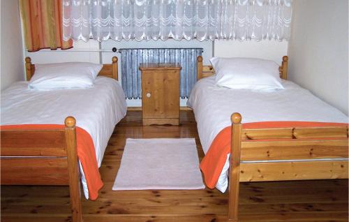a bedroom with two beds and a window with curtains at Awesome Home In Darlowo With Kitchen in Darłowo