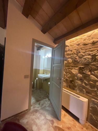uma casa de banho com uma parede de pedra ao lado de uma porta em Modus Aquae em Brisighella