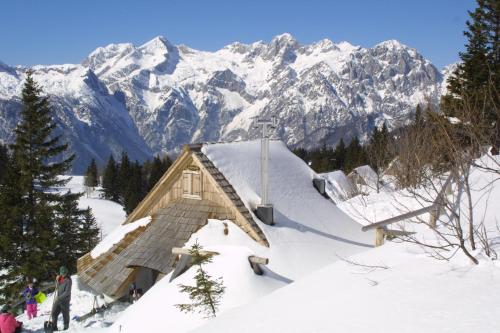 a small building in the snow with mountains in the background at Guest House Kraljev Hrib in Kamniška Bistrica
