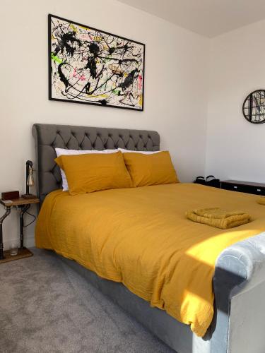 a bedroom with a bed with a yellow blanket at Stylish 2 Bed Apt, 2 Minute Walk From The Beach. in Sheringham