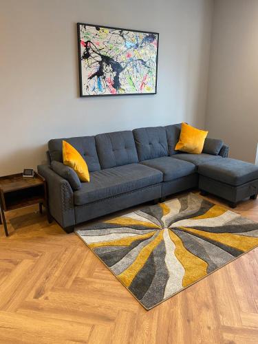 a living room with a blue couch and a rug at Stylish 2 Bed Apt, 2 Minute Walk From The Beach. in Sheringham