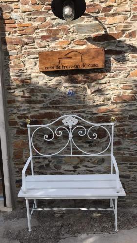 a white bench sitting in front of a stone wall at Casa da Travessa do Casal in Alqueve
