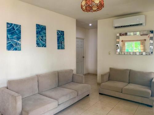a living room with two couches and paintings on the wall at Casa en Altata Las Aguilas, Nav. Sinaloa in Altata