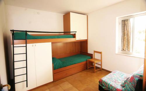 ein Schlafzimmer mit Etagenbetten mit einem Stuhl und einem Fenster in der Unterkunft Village GEMINI in Peschici