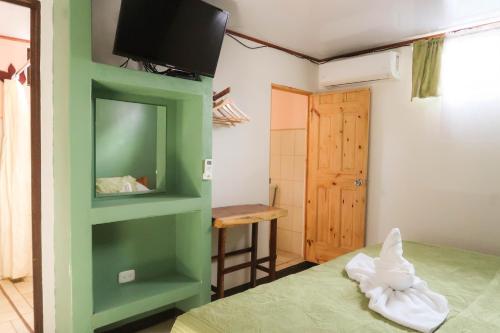 a room with a bed and a tv on a wall at Hotel Hoja de Oro Corcovado in Puerto Jiménez